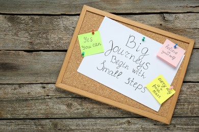 Photo of Corkboard with motivational quotes on wooden table, top view