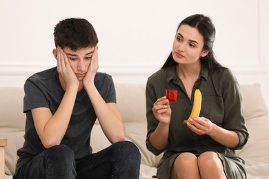 Photo of Mother talking with her teenage son about contraception at home. Sex education concept