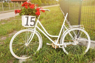 Photo of White bicycle with red flowers in basket on street