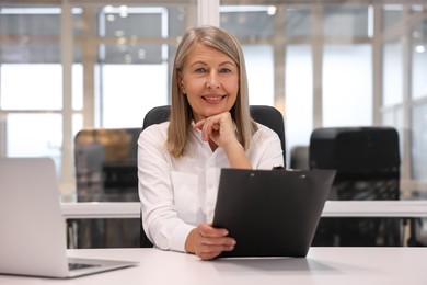 Smiling woman with clipboard working in office. Lawyer, businesswoman, accountant or manager