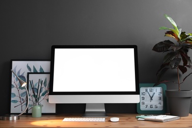 Comfortable workplace with modern computer on wooden table near black wall. Space for text