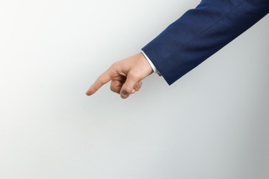 Photo of Man pointing at something on light background, closeup