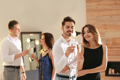 Friends clinking glasses with champagne at party indoors