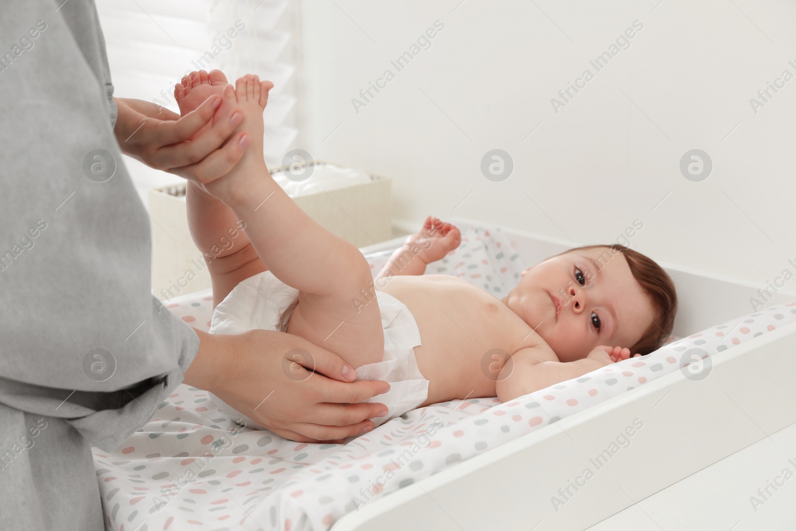 Photo of Mother changing baby's diaper on table at home, closeup