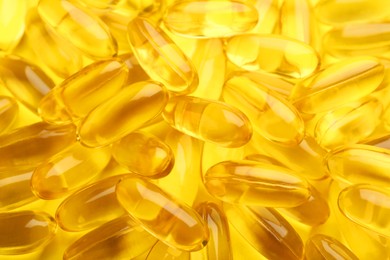 Photo of Many vitamin capsules on yellow background, closeup