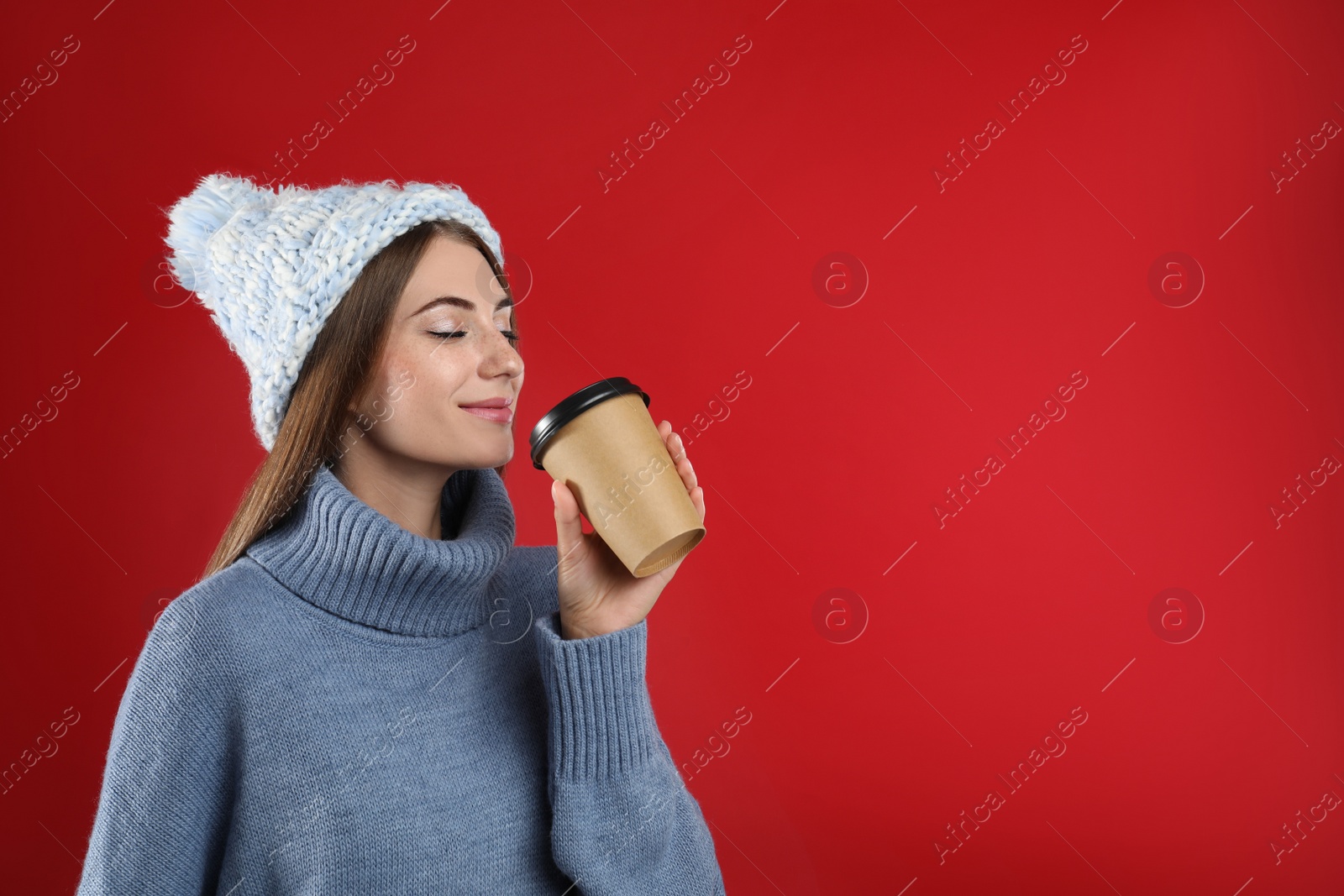 Photo of Happy beautiful woman with paper cup of mulled wine on red background. Space for text