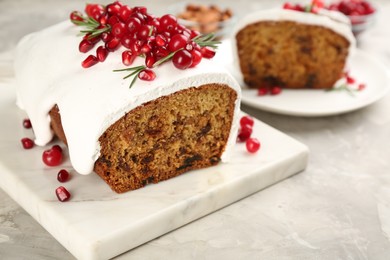 Traditional classic Christmas cake decorated with cranberries, pomegranate seeds and rosemary on light table