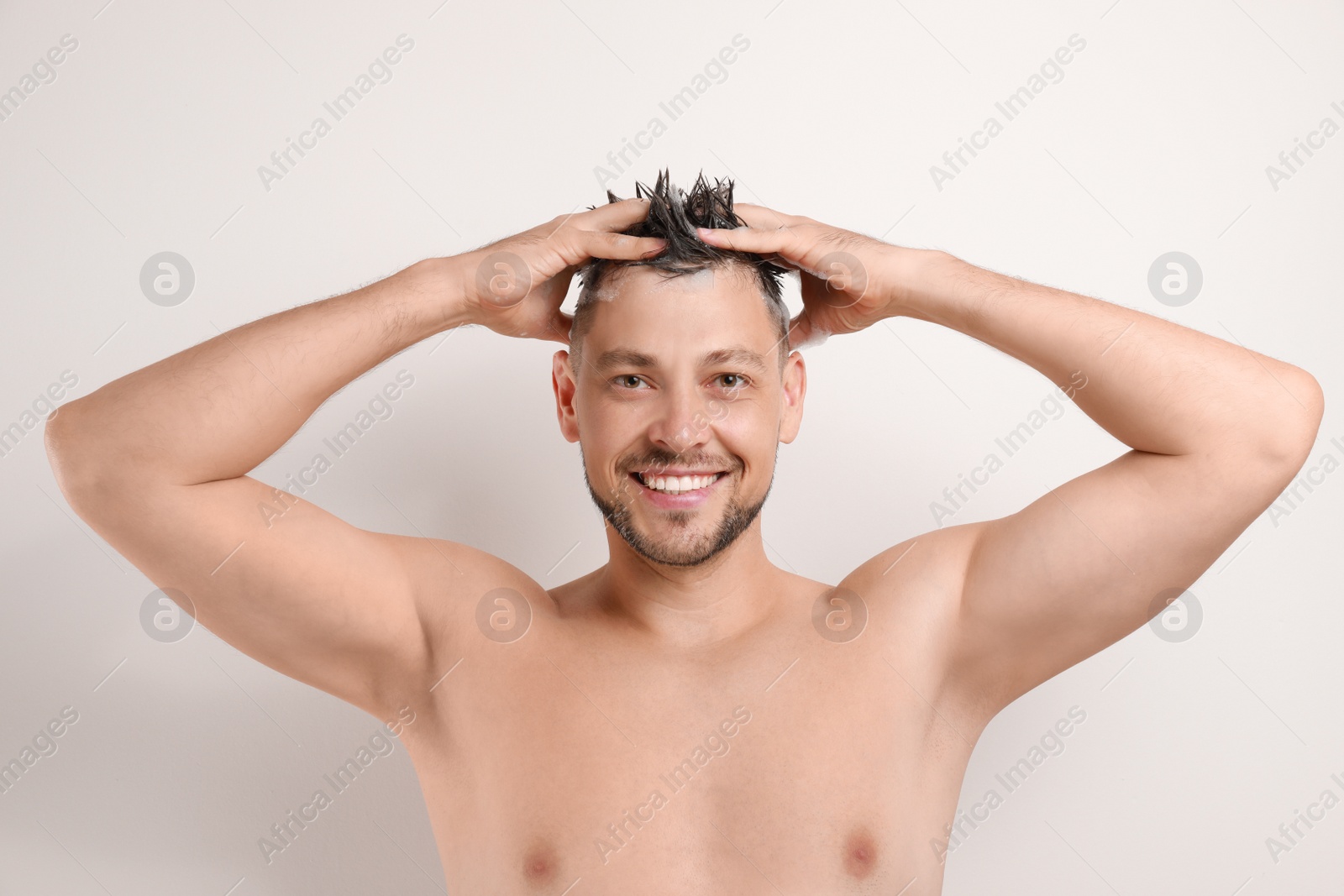 Photo of Handsome man washing hair on white background