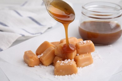 Pouring delicious salted caramel on candies on white table