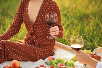 Photo of Young couple with wine having picnic in green park, closeup