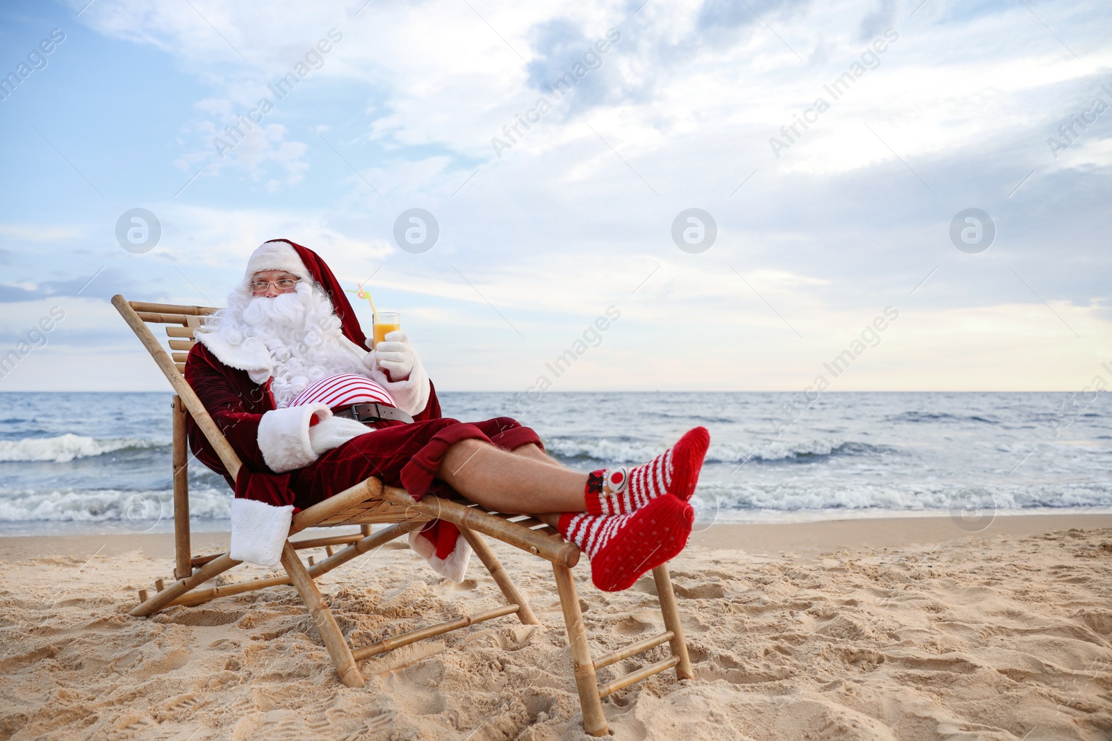 Photo of Santa Claus with cocktail relaxing on beach, space for text. Christmas vacation