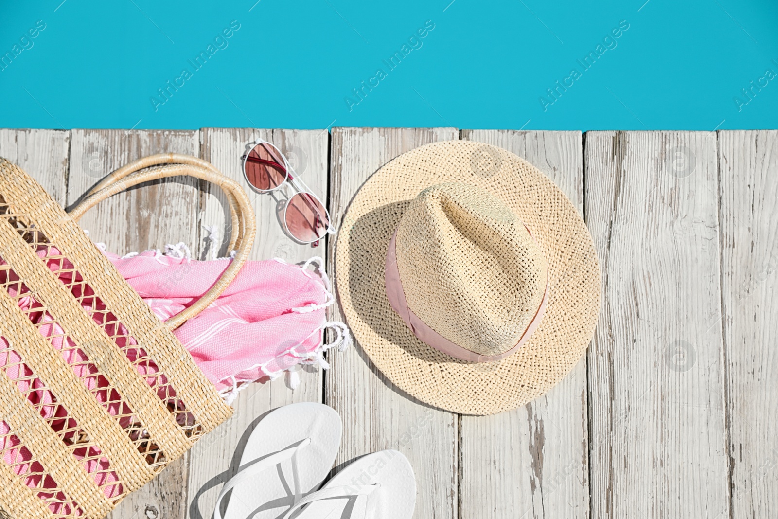 Photo of Beach accessories on wooden deck near outdoor swimming pool, flat lay