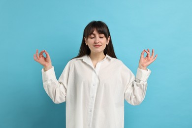 Photo of Woman in pyjama meditating on light blue background