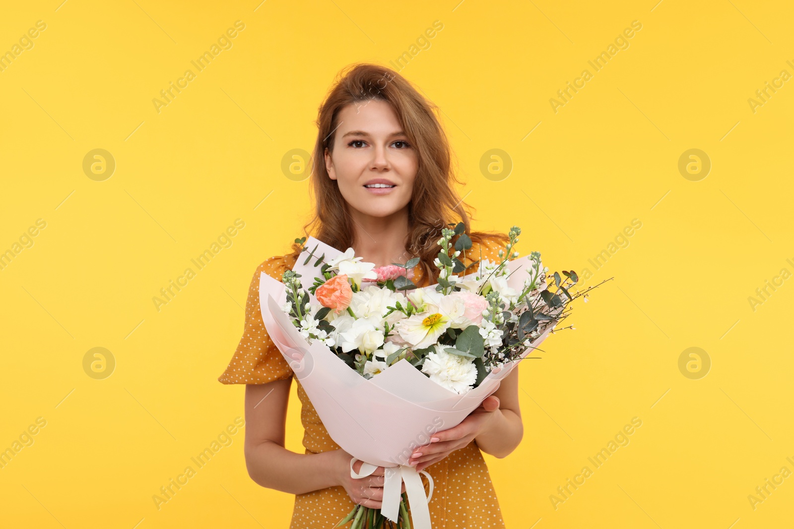 Photo of Happy woman with bouquet of beautiful flowers on yellow background