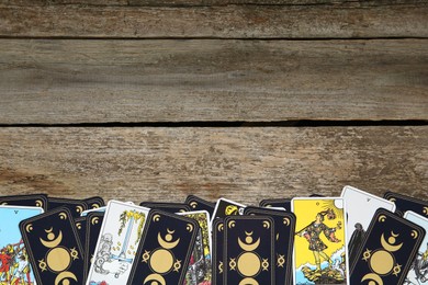 Photo of Tarot cards on wooden table, top view. Space for text