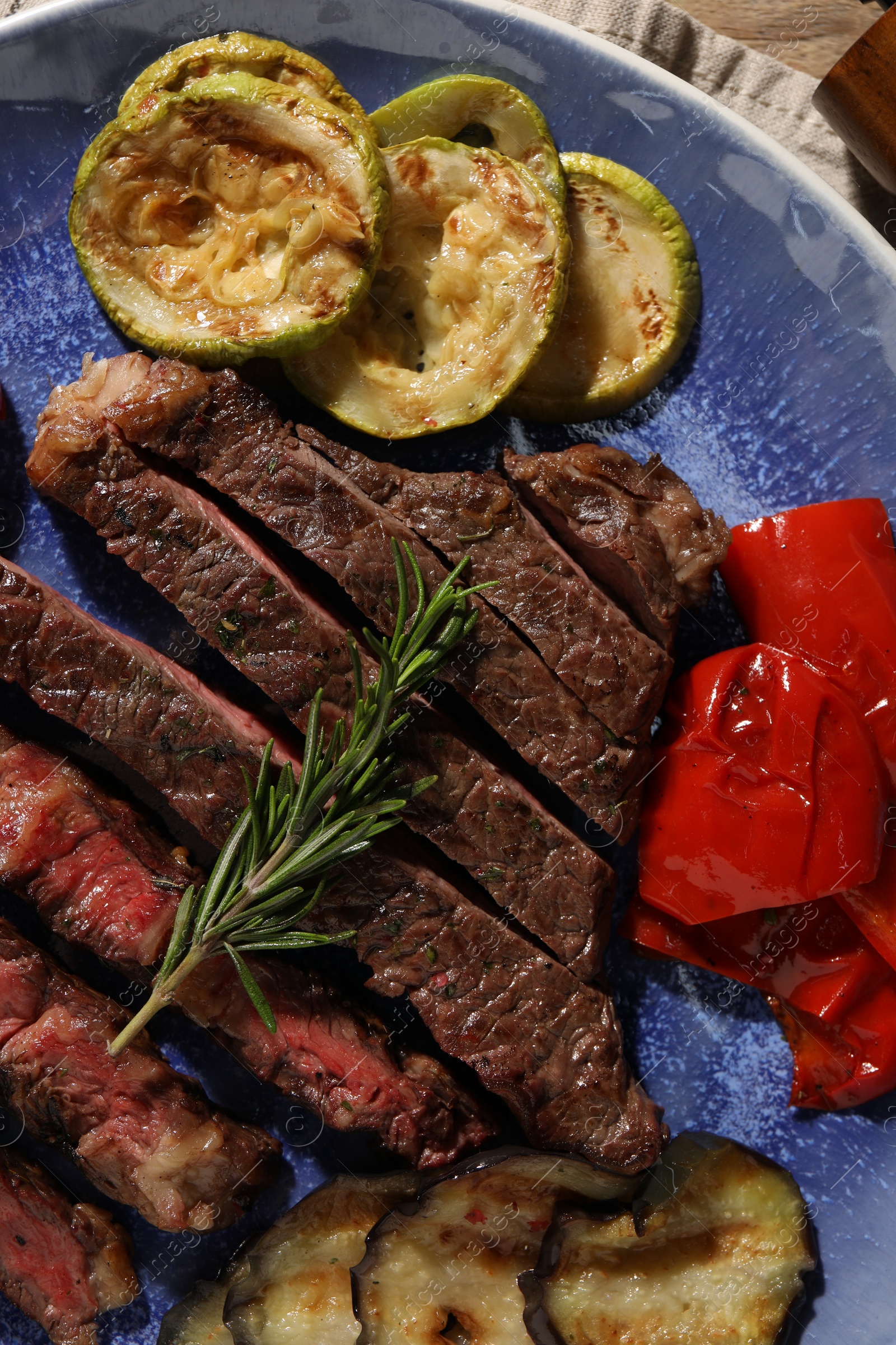 Photo of Delicious grilled beef steak with vegetables and spices on plate, top view