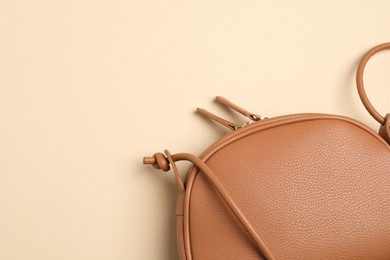 Photo of Stylish leather handbag on beige background, closeup. Space for text
