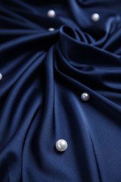 Many beautiful pearls on delicate dark blue silk, closeup