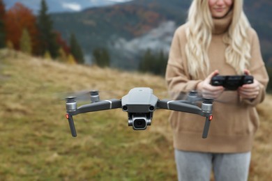 Photo of Woman operating modern drone with remote control in mountains