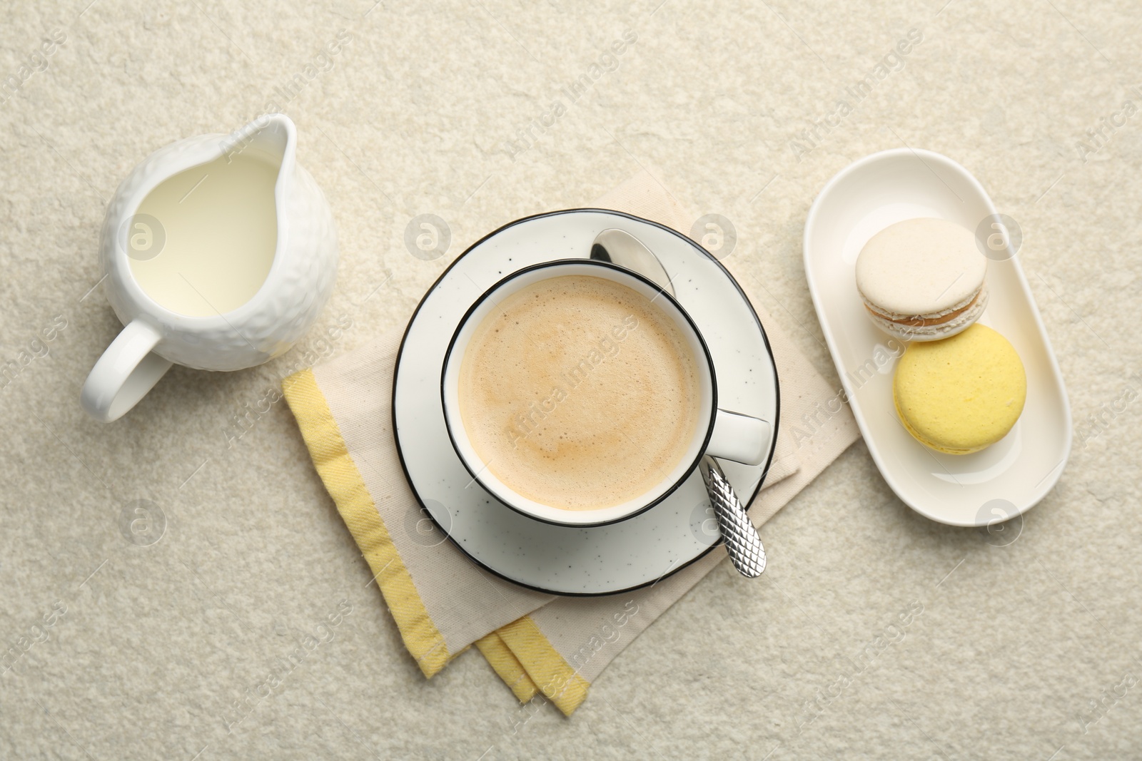 Photo of Tasty cappuccino in cup, milk and macarons on light textured table, flat lay