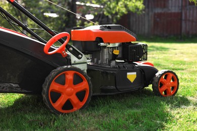 Modern lawn mower on green grass outdoors