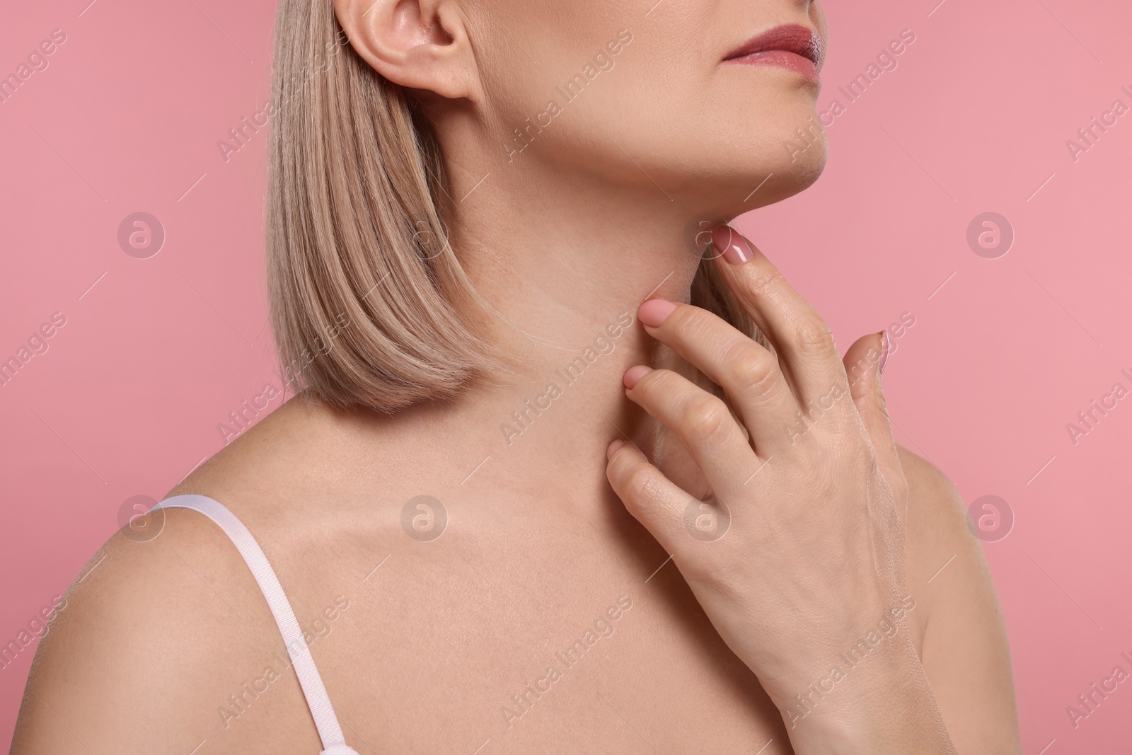 Photo of Woman touching her neck on pink background, closeup