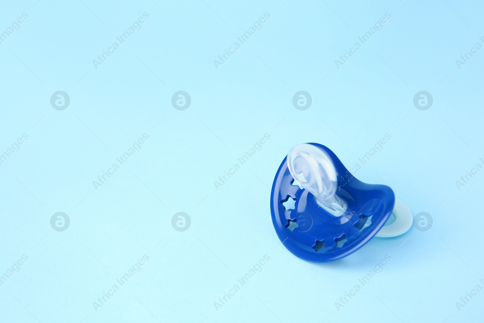 Photo of One baby pacifier on light blue background. Space for text