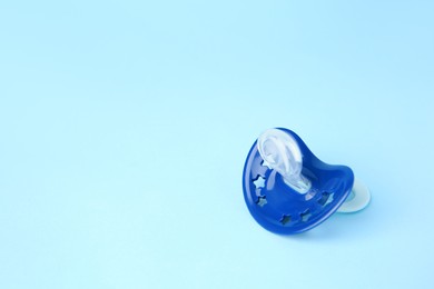 Photo of One baby pacifier on light blue background. Space for text
