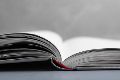 Open book with hard cover on grey table, closeup