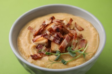 Photo of Delicious lentil soup with bacon and croutons on green background, closeup