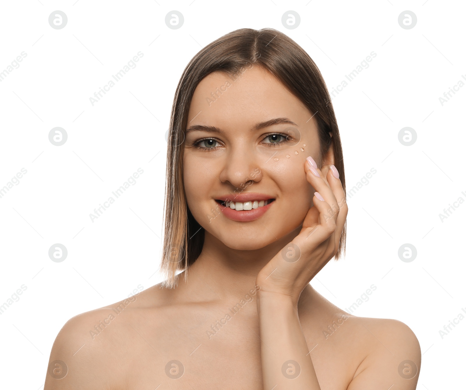 Photo of Young woman applying cream under eyes on white background