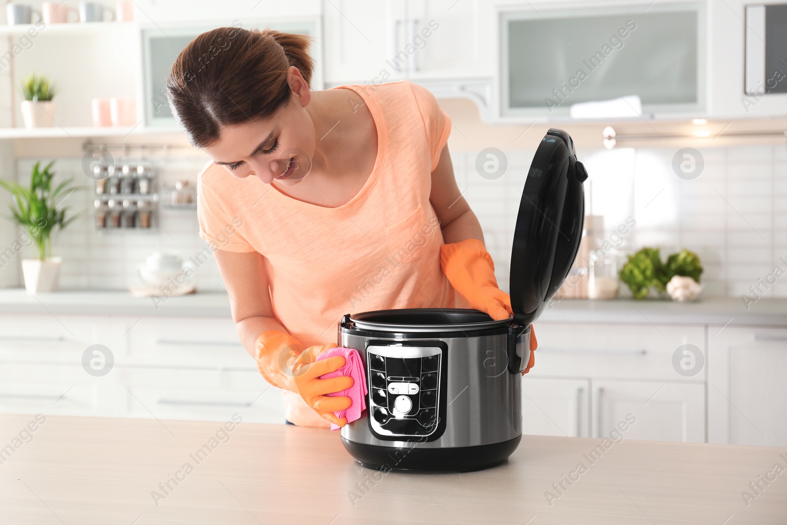 Photo of Woman cleaning modern multi cooker at table in kitchen