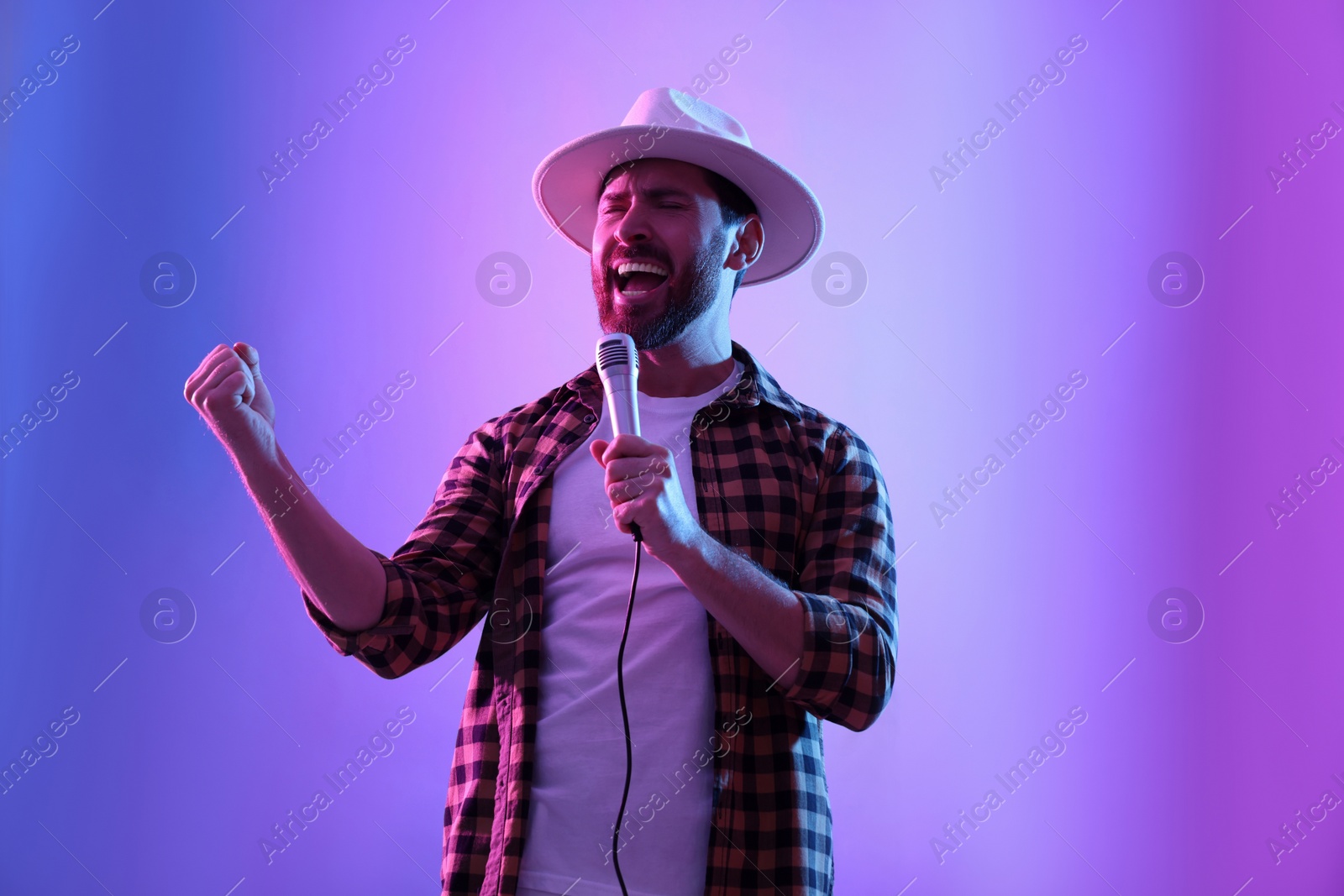 Photo of Emotional man with microphone singing in neon lights