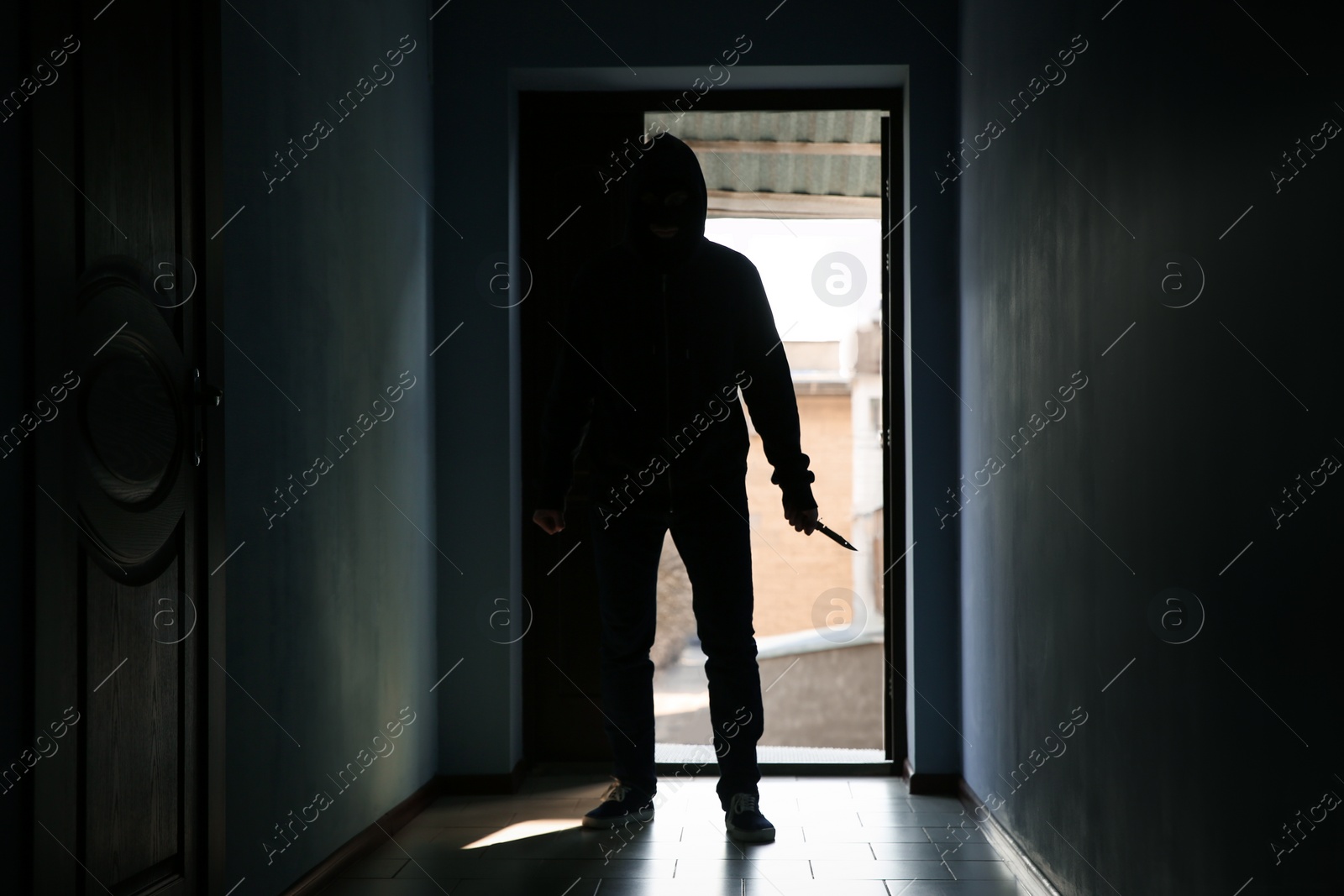 Photo of Man with knife in dark room. Dangerous criminal