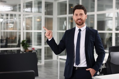 Photo of Happy real estate agent pointing in office