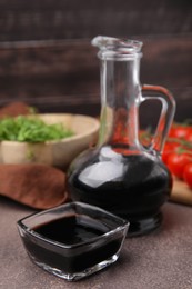 Photo of Organic balsamic vinegar, tomatoes and greens on grey table