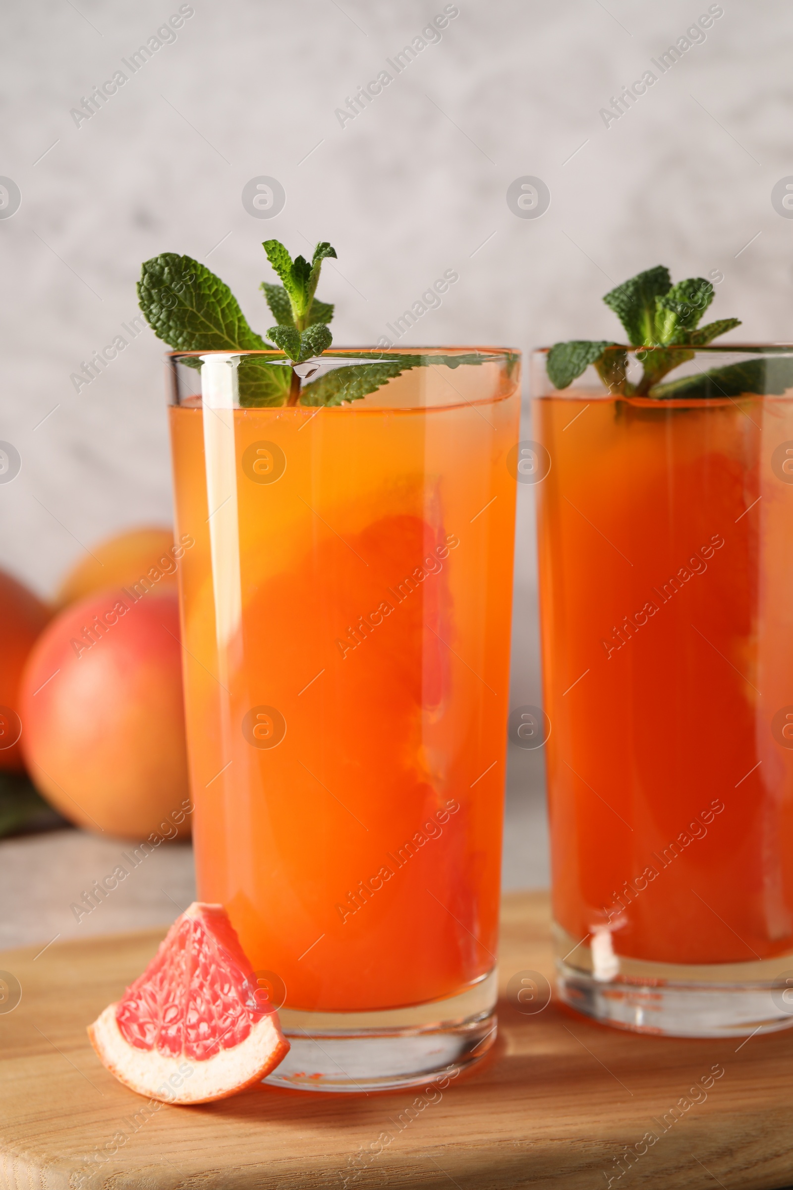 Photo of Tasty freshly made grapefruit juice, fruit and mint on table, closeup