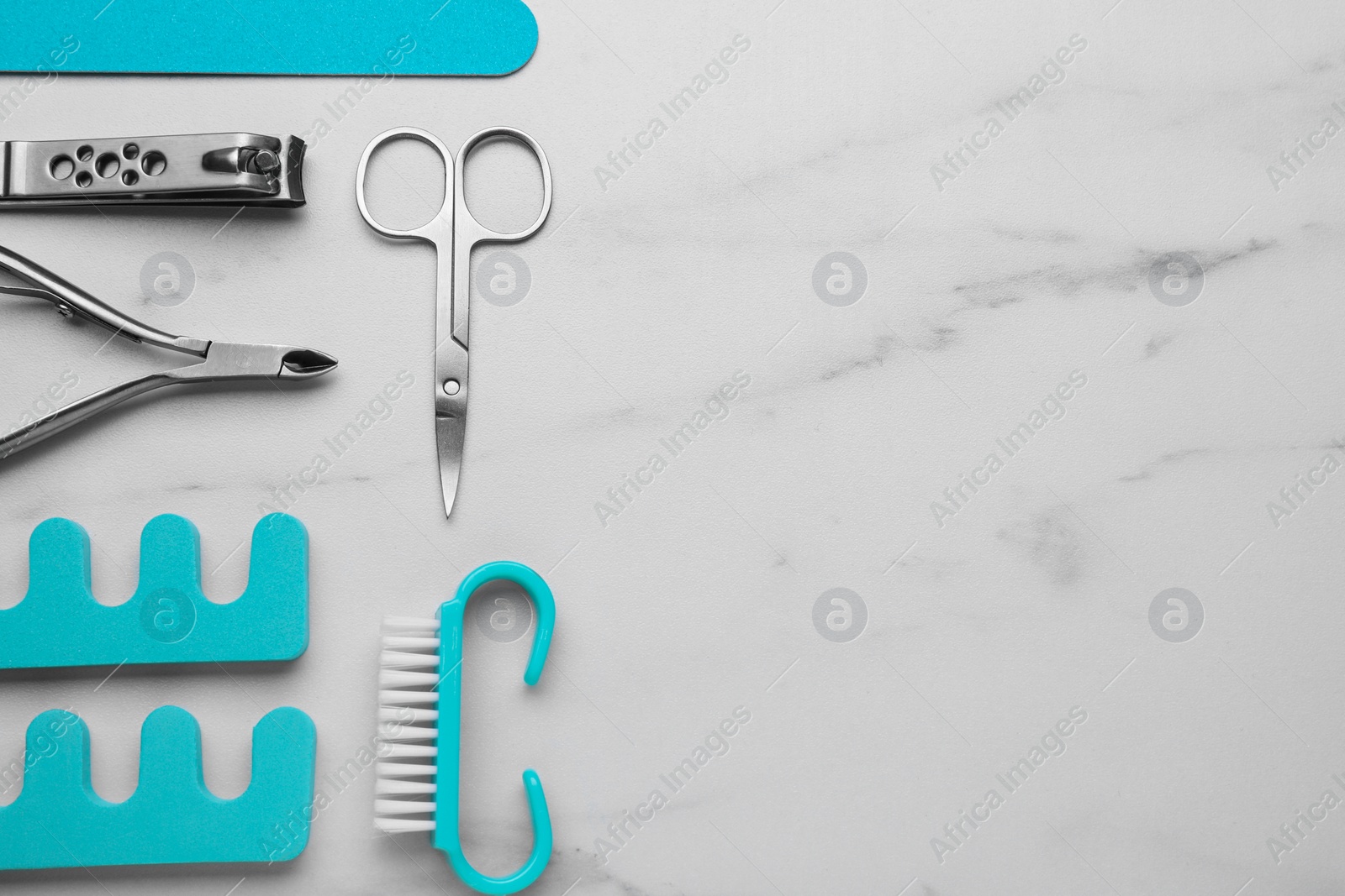 Photo of Set of pedicure tools on white marble table, flat lay. Space for text