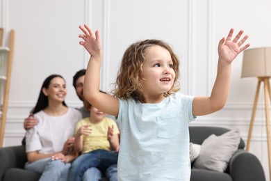 Photo of Happy family having fun at home. Daughter dancing while her relatives resting on sofa
