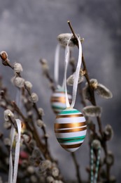 Photo of Beautiful willow branches with painted eggs on light grey background, closeup. Easter decor