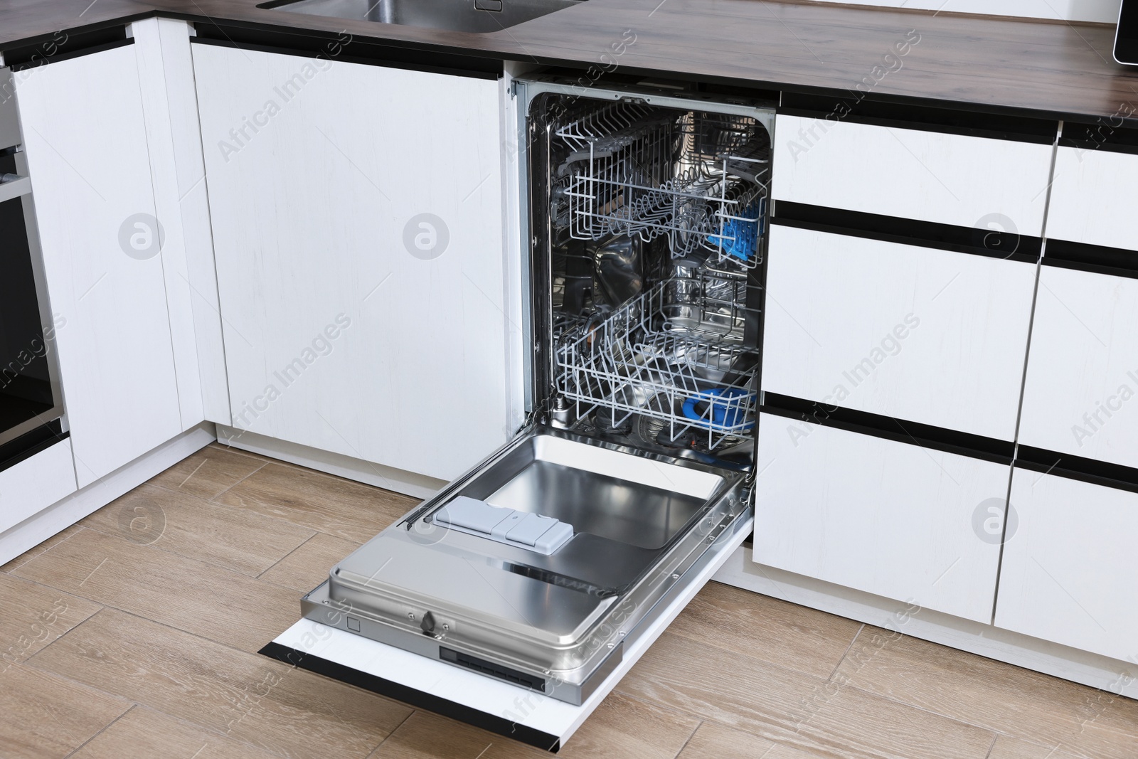 Photo of Open clean empty dishwasher in kitchen. Home appliance