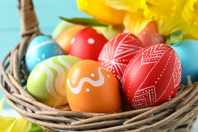 Painted Easter eggs in wicker basket, closeup