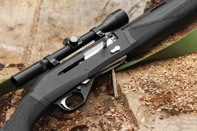 Hunting rifle on tree stump outdoors, closeup