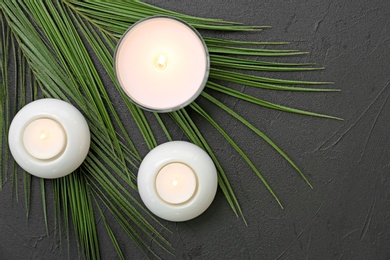 Photo of Burning candles and leaves on grey background. Spa composition