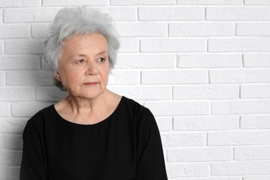 Photo of Portrait of mature woman near brick wall. Space for text