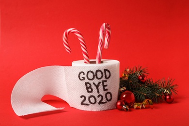 Photo of Toilet paper roll with text Goodbye 2020 and Christmas decor on red background