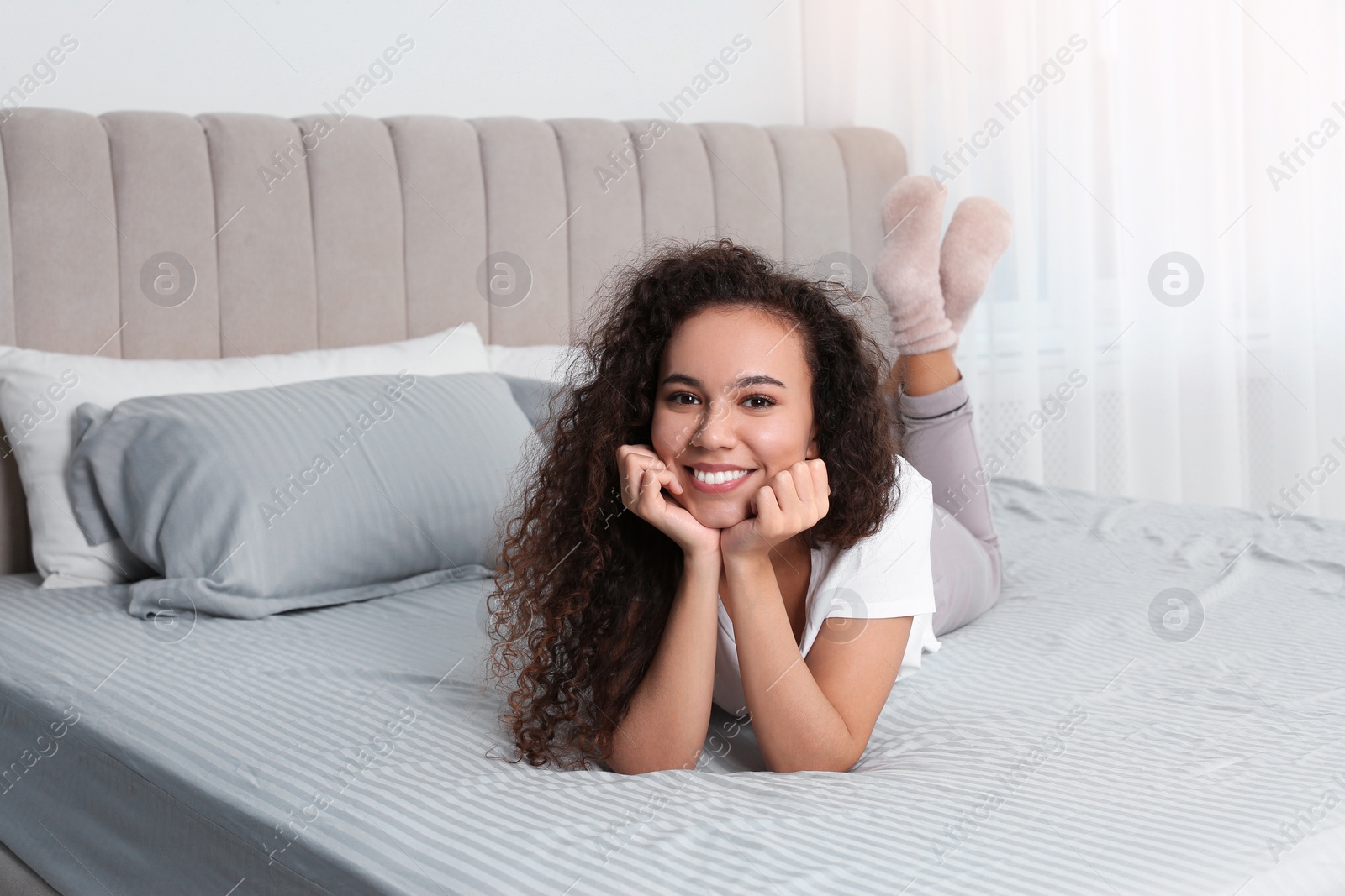 Photo of Happy beautiful African American woman lying on bed at home
