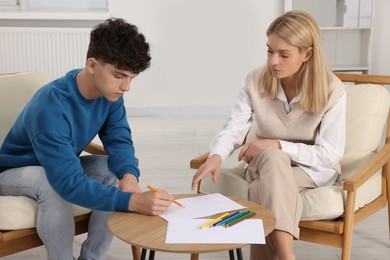 Photo of Psychologist working with teenage boy in office. Teenager problems