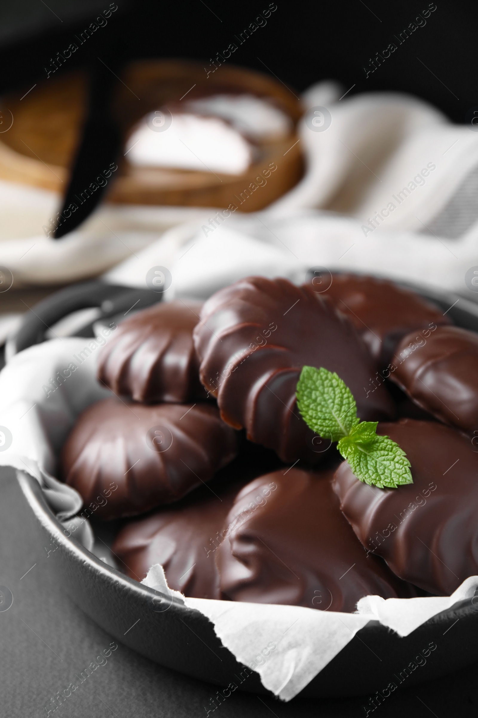 Photo of Delicious chocolate covered marshmallows with mint on black table, closeup