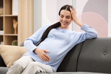 Photo of Happy pregnant woman on sofa at home